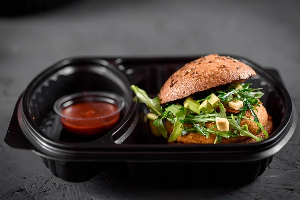 Vegetarian burger with red sauce in black box