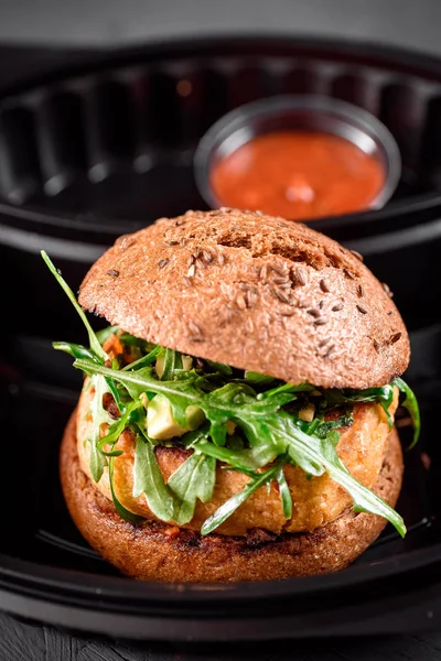 Vegetarian burger with red sauce in black box