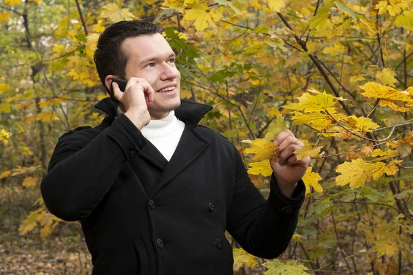 Young man talking on cellphone at park — Stock Photo, Image