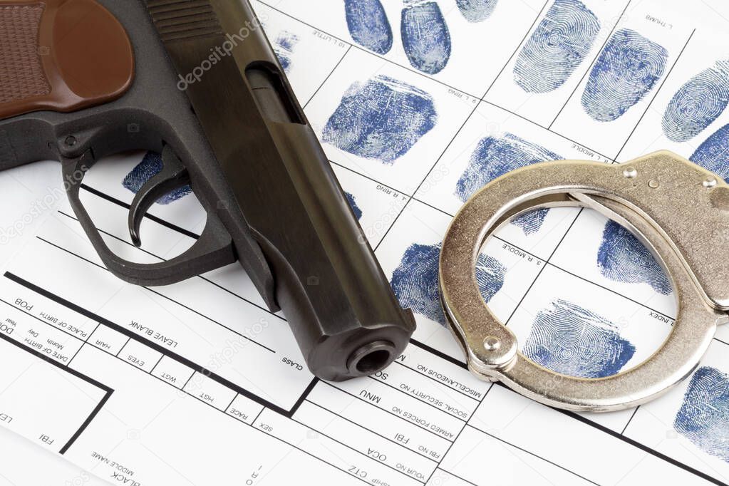 Fingerprint card with handcuffs and gun close-up