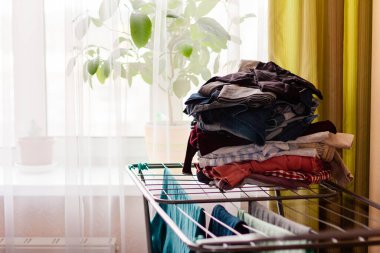 Pencerenin yanındaki dairede renkli giysiler için kuru askı.