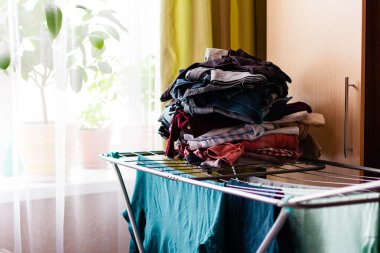 Pencerenin yanındaki dairede renkli giysiler için kuru askı.