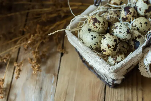 Quail eggs in wire basket with dry beige flowers on barn wood, Easter, vintage, rustic style — Stock Photo, Image