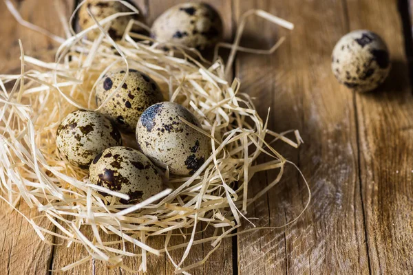 Huevos de codorniz dispersos en un nido de paja sobre fondo de madera, parientes, Pascua, agricultura — Foto de Stock