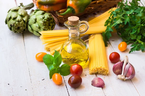 Cucina italiana, ingredienti per una cena sana, olio d'oliva, pomodori, basilico, aglio, spaghetti, carciofi, verdure, erbe aromatiche — Foto Stock