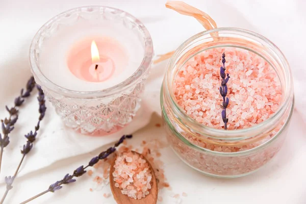 Růžová himálajská sůl do sklenic, hořící svíčka dřevěná lžíce, levandule na bílé bavlněné tkaniny, stylizované fotografie pro sociální média — Stock fotografie