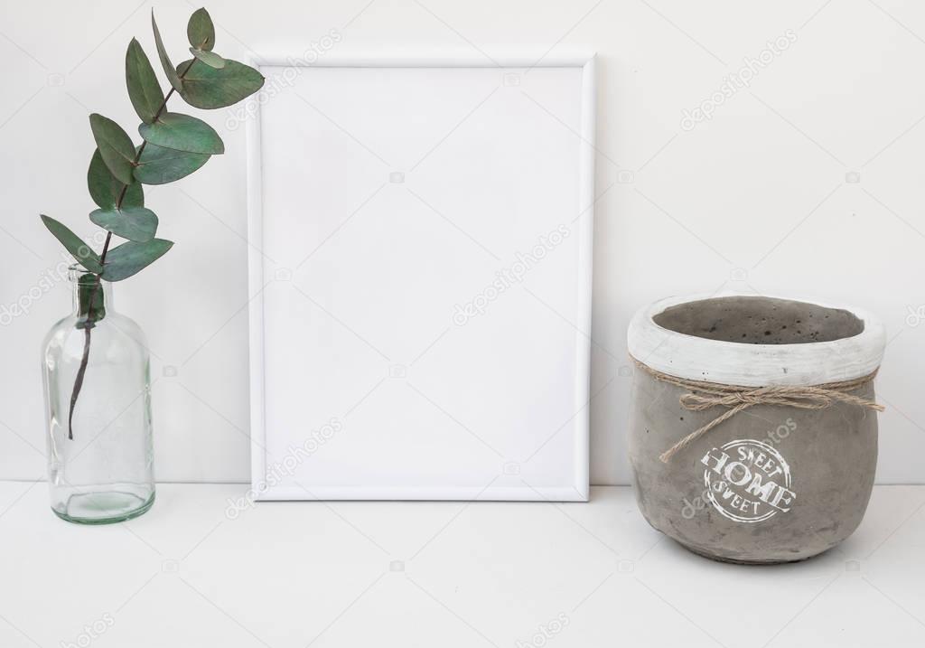 White frame mockup, eucalyptus branch in glass bottle, cement bowl, styled minimalist clean image for product marketing