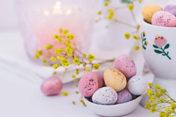 Čokoládová Velikonoční Vajíčka Pastelových Barvách Keramické Lžíci Hořící Svíčka Bílý — Stock fotografie