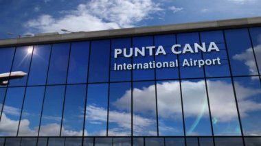 Punta Cana, Dominik Cumhuriyeti 'ne iniş yapan bir jet uçağı. Cam havaalanı terminali ve uçak yansıması olan şehre varış. Seyahat, iş, turizm ve ulaşım.