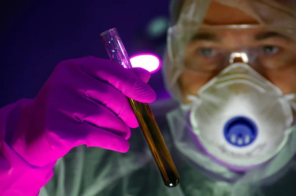 Scientist in mask and protection glass with test-tube in glove hand. Concept of laboratory, science research, biology, chemistry experiment, biotechnology, health, medical, virus search and pharmacy.