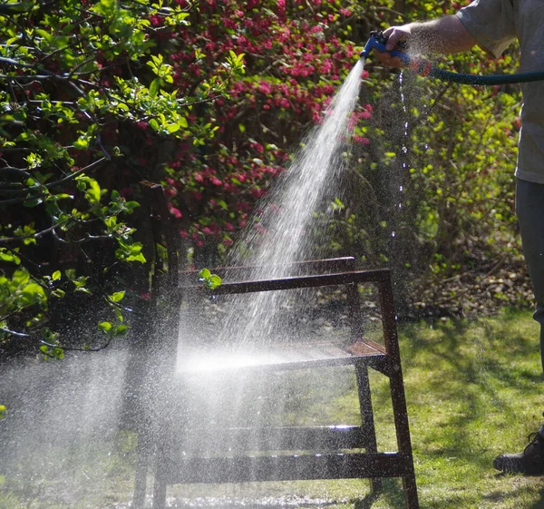 Mycie Mebli Ogrodowych Wiosną Człowiek Szczytuje Drewniane Krzesło Strumieniem Wody — Zdjęcie stockowe
