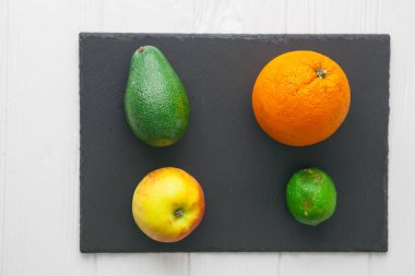 avokado, elma portakal ve limon taş tahta üzerinde