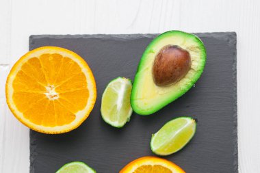 avokado, portakal ve limon taş tahta üzerinde