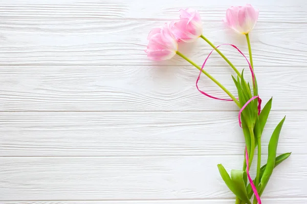 Ahşap beyaz arka plan ve Pembe Lale. Mart 8, anneler günü.