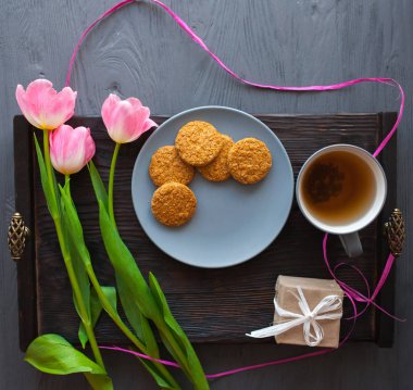 Anneler günü, kadının gün. Lale, hediyeler, çay ve tatlılar ahşap arka plan üzerinde