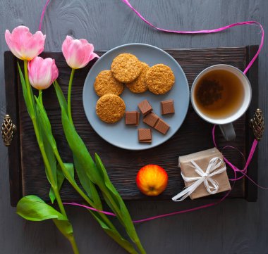 Anneler günü, kadının gün. Lale, hediyeler, çay ve tatlılar ahşap arka plan üzerinde