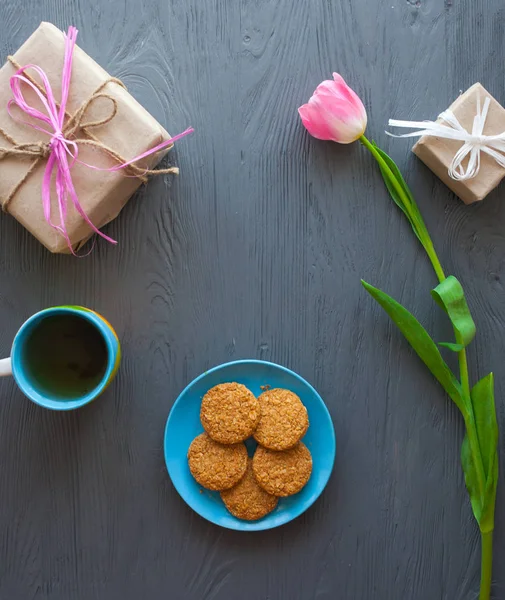 Anneler günü, kadının gün. Lale, hediyeler, çay ve tatlılar ahşap arka plan üzerinde