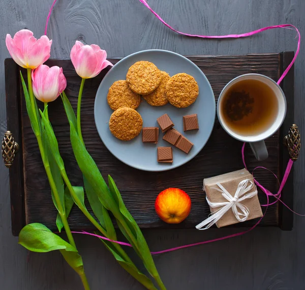 Anneler günü, kadının gün. Lale, hediyeler, çay ve tatlılar ahşap arka plan üzerinde