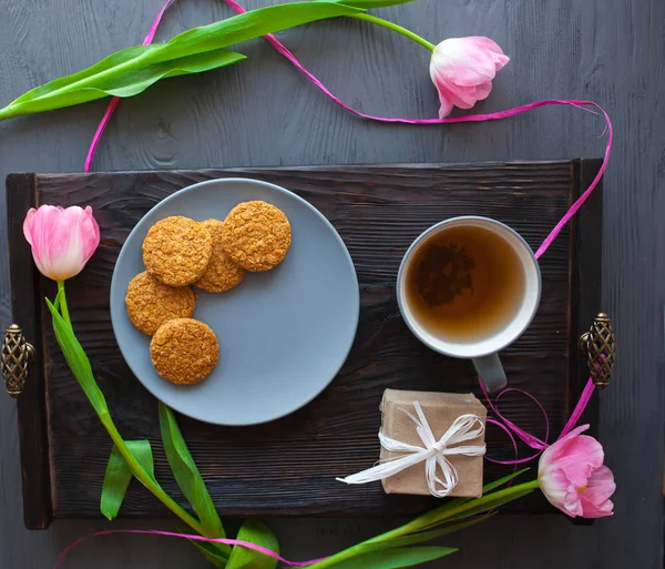День матери, женский день. тюльпаны, подарки, чай и сладости на деревянном фоне Лицензионные Стоковые Фото