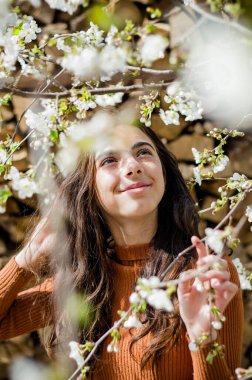 Ağacın yanında beyaz çiçekli bir kızın portresi.