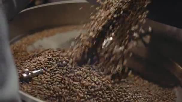 Freshly roasted coffee beans on a cooling tray, being mixed by a rotating mechanical arm, then being emptied. — Stock Video