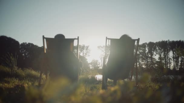 Deux amants hommes et femmes se joignent à la main sur le fond du lac Sunset — Video