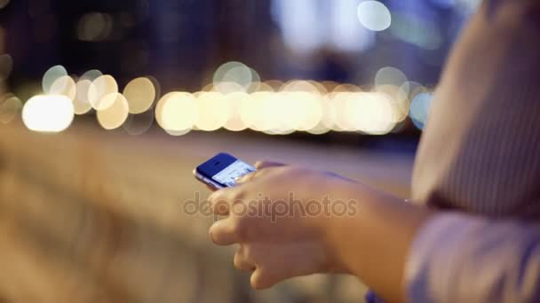 Closeup of young woman hands scrolling pictures phone in night — Stock Video