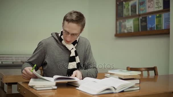 Student, czytając książkę w bibliotece, siedział przy stole, poruszać kamerą — Wideo stockowe