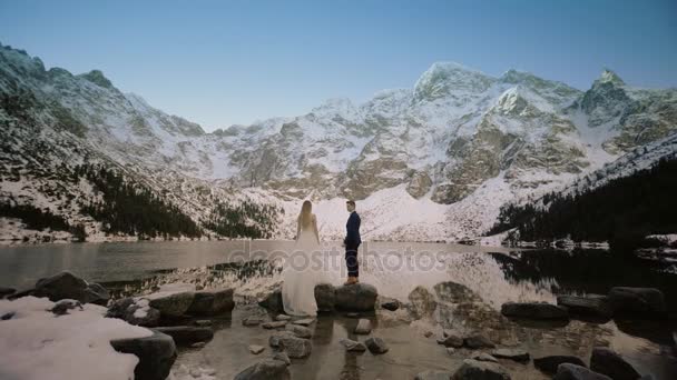 Наречені стоять на тлі гір взимку — стокове відео