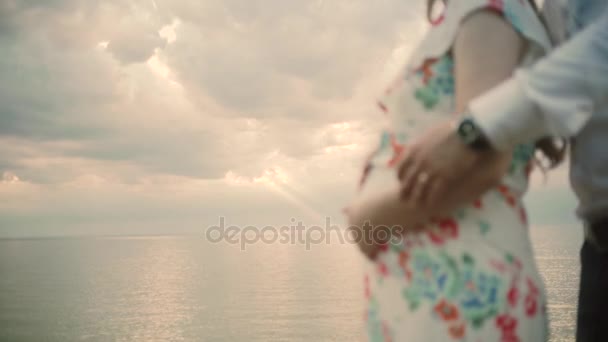 Pregnant couple standing on the beach and Man caressing womans belly and hugging woman — Stock Video