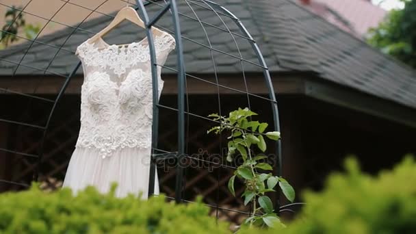 Bílé krajkové svatební šaty visí na krásném místě. Closeup — Stock video