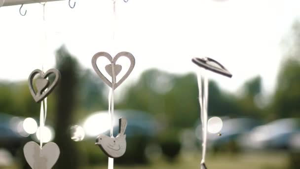 Beautiful outdoors holiday decoration. Wooden hearts and birds slowly moving on wind. close up — Stock Video