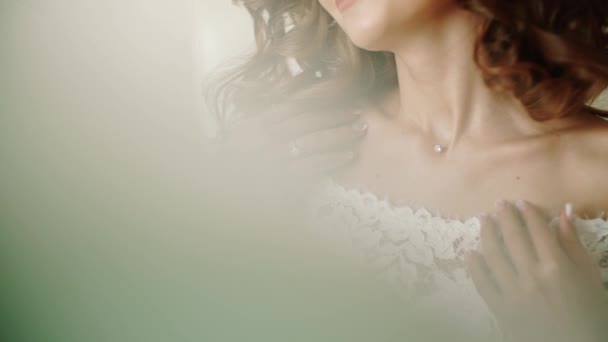 La sposa con un'acconciatura nuziale aggiusta gioielli su un collo. Prepararsi per la celebrazione . — Video Stock