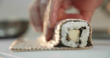 Suşi hazırlama süreci. Suşi rulosunu yuvarlıyor. Suşi ruloları için malzeme istiflemek - pirinç, salatalık, feta peyniri, somon yavaş çekim. Kapat.