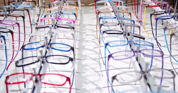 Kapatın. Sergilenen gözlükler. Raflarda satılık bir sürü farklı gözlük gözlüğü olan bir optometrist mağazası. Kaydırma videosu — Stok video
