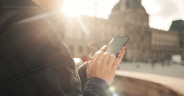 Mujer mira y toma fotos con la cámara del teléfono en el día soleado fuera en París Francia Europa. De cerca. — Vídeos de Stock