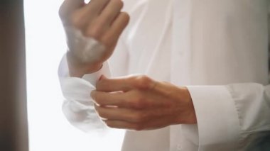 Adam beyaz gömleğini bağlıyor. Kapat.