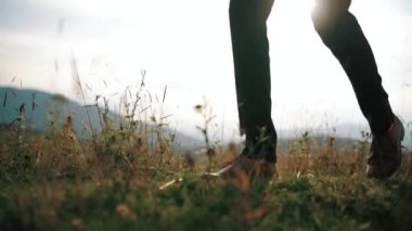 Damat ya da işveren bacakları güneş ışınları altında dik arazide, adımlar atıyor, yürüyüş yapıyor, yakın çekim yapıyor. Yavaş çekim