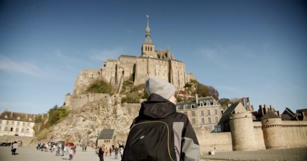 Fotografía cinematográfica, Mujer joven con mochila va a la hermosa isla de Mont Saint Michel, Normandía — Vídeos de Stock