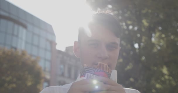 En cámara lenta. Feliz joven adolescente comiendo sabroso sándwich, en el parque al aire libre . — Vídeos de Stock