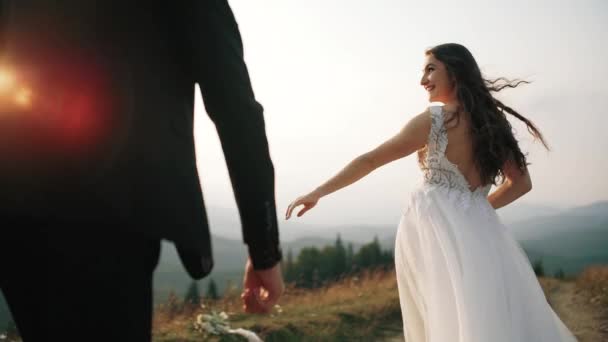 Lo sposo corre per la sposa su colline di montagna. Rallentatore, Midle shot — Video Stock