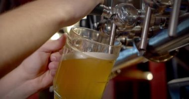 Ağır çekim. Barmen bardağa bira dolduruyor. Kapat.
