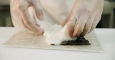 Restoran mutfağı. Erkek suşi şefi Japon suşi ruloları pilav, somon, avokado ve nori hazırlıyor. Eller yukarı..