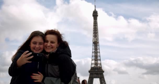 Счастливая любящая мать и дочь делают селфи на смартфоне и обнимаются вместе, на фоне Эльфеля в солнечный день, Франция — стоковое видео