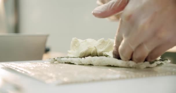 Restaurantküche männlicher Sushi-Chef bereitet japanische Sushi-Rollen aus Reis, Lachs, Avocado und Nori zu. legt Käse auf das Sushi — Stockvideo