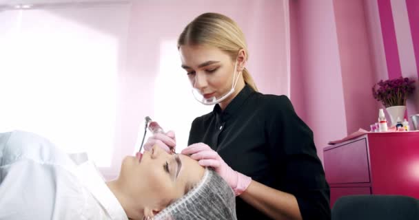 Improving and correction the shape of eyebrows in a beauty parlor. A ethod of eyebrow correction with powder spraying. Microblading, eyebrow tattoo, Permanent makeup. Slow motion. Wide shot — Stock Video