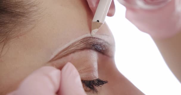 De cerca. Marcando la forma de las cejas. Preparación para el tatuaje. Crear maquillaje permanente de cejas. .. Movimiento lento — Vídeos de Stock