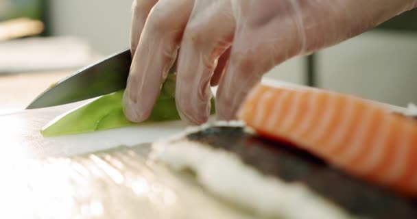 Restaurant keuken. Mannelijke sushi chef bereidt Japanse sushi rollen rijst, zalm, avocado en nori. bereidt avocado 's — Stockvideo