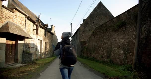 Increíble rodaje cinematográfico, mujer joven caminando por hermosas calles con casas de piedra en el pueblo. Vista amplia — Vídeo de stock