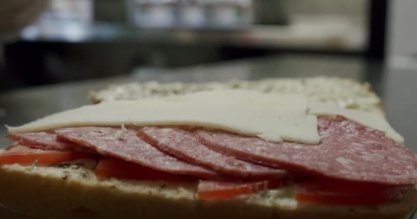 Chica haciendo sándwich con salami. Pone queso en la salchicha en el sándwich. Movimiento lento — Vídeo de stock